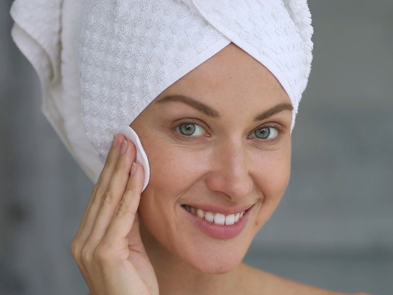 devojka sa peškirom na glavi čisti svoje lice sa tupferom